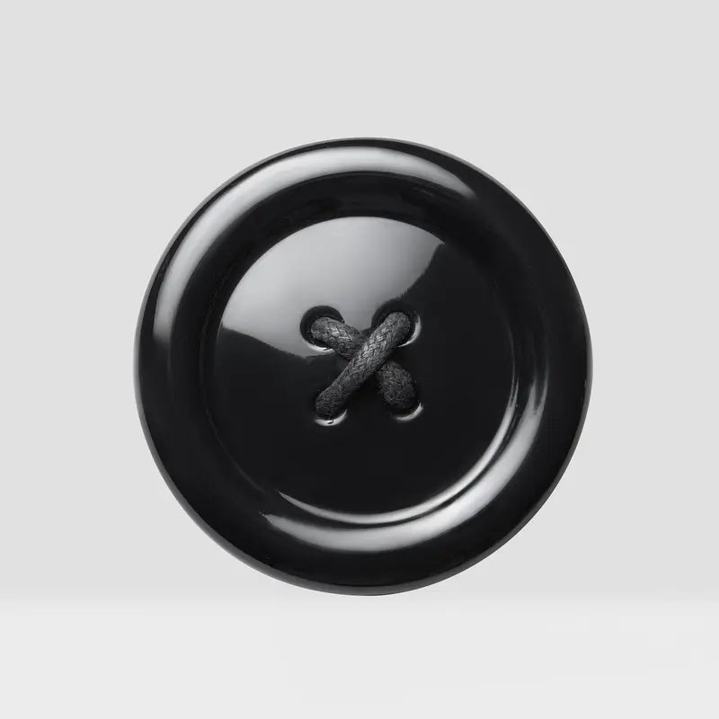 Black button with a threaded design, inspired by the Beauty Creations Coraline Button Eyes Compact Mirror.
