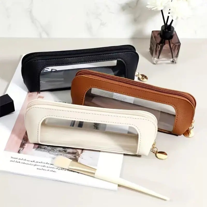 Portable Makeup Brush & Cosmetic Bag in black, brown, and cream colors on a desk with a makeup brush.